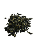 A small pile of Iron Goddess of mercy Oolong tea leaves with lighter yellow-green tips, photographed on a plain white background.