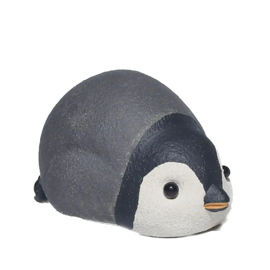 A small penguin-shaped tea pet named Waddle with a textured dark gray chubby body, black and white face, and a tiny orange beak, shown on a plain white background.
