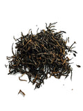 A small pile of loose-leaf Jin Jun Mei tea leaves, primarily dark brown with lighter golden-brown tips, scattered on a plain white background.