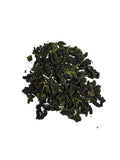 A small pile of dark green, tightly rolled loose-leaf Iron goddess tea on a plain white background.